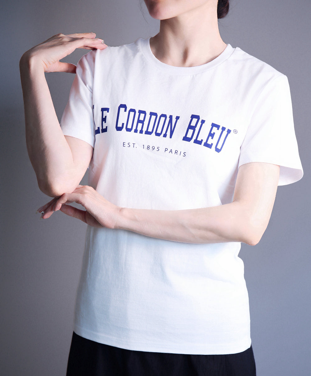 Person wearing a white t-shirt with 'LE CORDON BLEU' text on a gray background